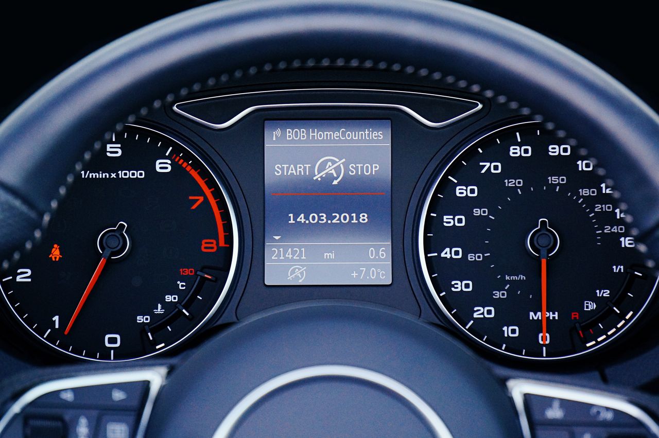 services-03 Close-up of a car dashboard displaying speedometer, tachometer, and digital display with mileage.